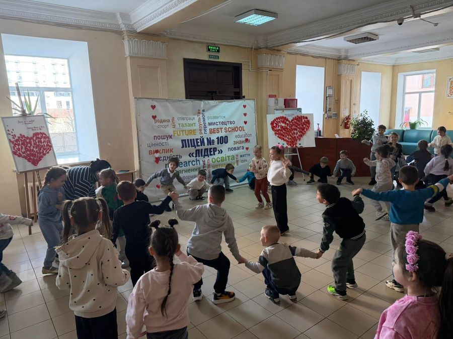Ведуча показує рух, діти повторюють за нею посеред холу